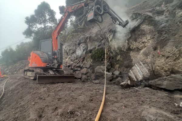 A construction drill mounted on excavation equipment working into a rocky slope as part of civil construction and retaining walls preparation. The image highlights drilling services, slope retention, rock anchors, soil nails and site contractors delivering complex construction projects.