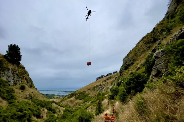 Helicopter operation lifting materials over Barnett Park during a staircase replacement and walking track construction project. The image shows civil contractors managing heli operation, commercial sling logistics, recreation construction, park construction and complex project management.