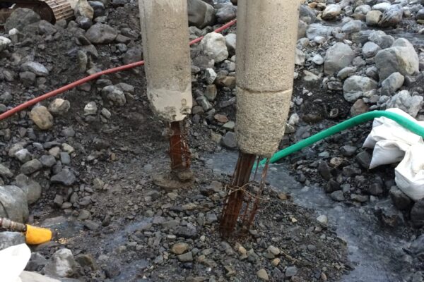 Close-up of bridge piles in a riverbed during bridge repair and bridge maintenance works, with civil contractors preparing the base of the structure. This image shows bridge inspection, bridge strengthening, driven piles, siteworks and civil construction in a challenging waterway environment.
