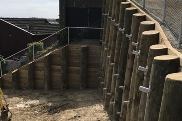 Completed timber retaining walls with visible mechanical anchors installed along the posts for slope retention and ground stabilisation. This image highlights civil construction, large scale retaining walls, anchoring and piling, concrete structure works and project management by civil contractors.