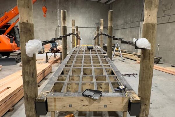 Timber bridge structure under construction inside a workshop with framing, posts and decking supports being assembled. The image highlights bridge construction, timber structures, structure construction and project management before site installation.