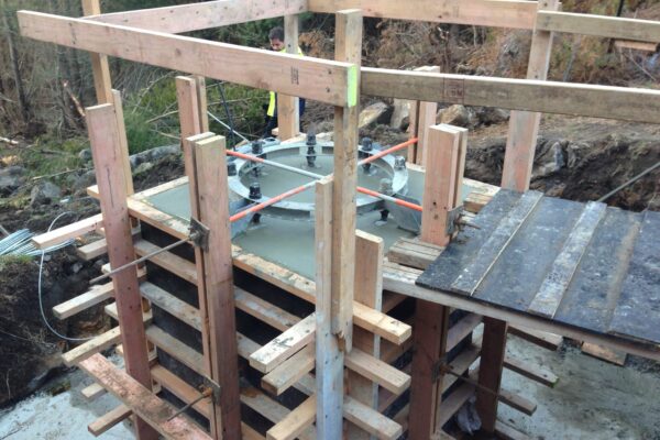 Timber formwork and concrete structure preparation underway for an adventure infrastructure foundation, with civil contractors setting up structure construction in a forested site. The image shows civil construction, foundation construction, siteworks and park construction being delivered in difficult terrain.