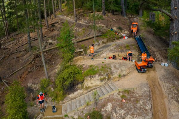 Aerial view of civil construction crews and machinery completing walking track construction through a forested hillside reserve. The project includes recreation construction, siteworks, erosion control and project management for improved public access.