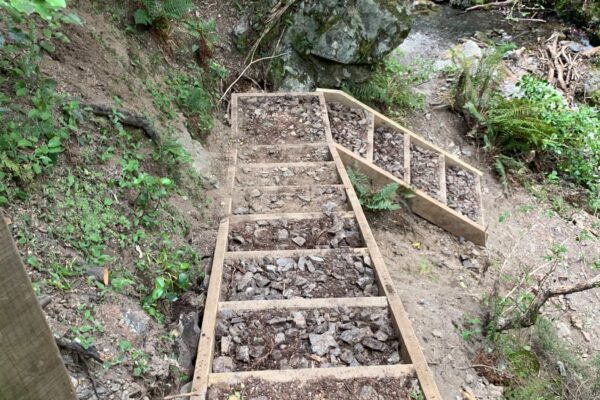 Timber boxed steps and handrail being constructed through a rocky bush track as part of Hanmer walking track construction. This image shows civil contractors completing recreation construction, erosion control, park construction and siteworks in steep natural terrain.