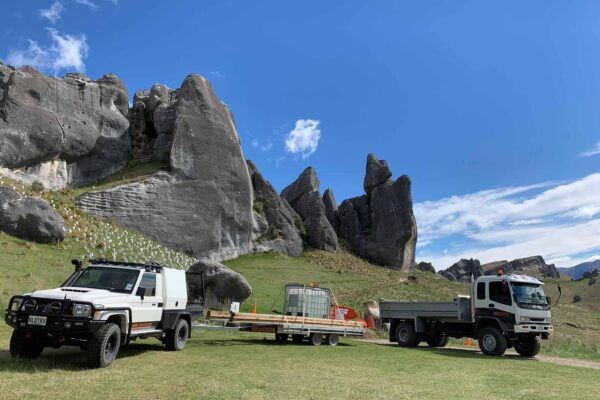 Civil contractors and site vehicles positioned below limestone rock formations during recreation construction and siteworks at Kura Tawhiti Castle Hill. The image shows project management, machinery transport, site preparation and park construction in a sensitive natural landscape.