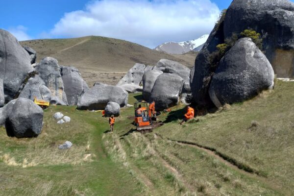 Civil contractors and excavation machinery completing walking track construction among limestone rock formations at Kura Tawhiti Castle Hill. This image highlights recreation construction, park construction, site preparation, siteworks and project management in a protected natural landscape.