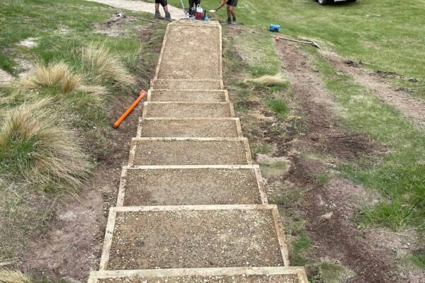 Timber boxed steps being built into a hillside as part of walking track construction and recreation construction at Kura Tawhiti Castle Hill. The image highlights civil contractors, siteworks, park construction, erosion control and site preparation in a scenic natural area.