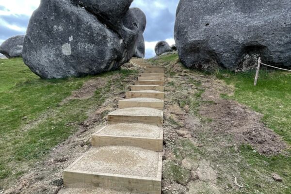 Completed timber steps forming a walking track between limestone formations at Kura Tawhiti Castle Hill. This image shows recreation construction, park construction, walking track construction, siteworks and erosion control delivered by civil contractors.