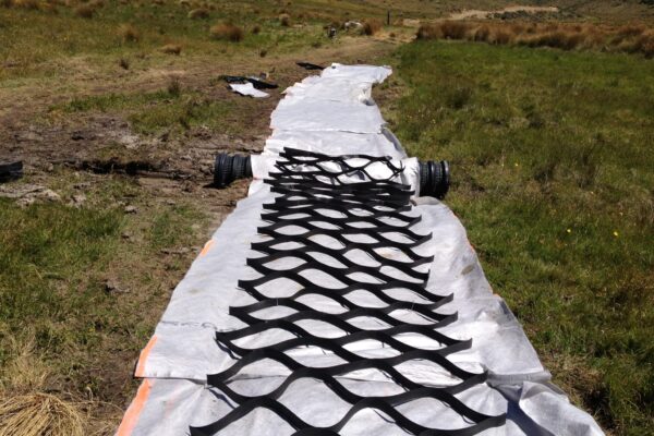 Erosion control matting installed along a rural track as part of walking track construction and civil construction works. The image shows civil contractors completing siteworks, ground stabilisation and recreation construction in an exposed natural landscape.