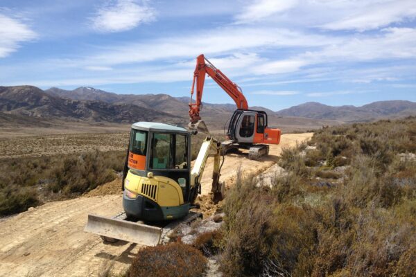 Excavation machinery shaping a remote walking track through open country, with civil contractors carrying out site preparation and track construction. This image highlights civil construction, walking track construction, earthworks contractors and recreation construction in difficult terrain.