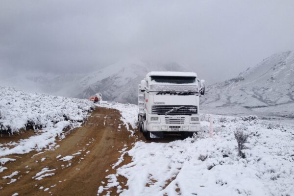 Machinery transport and civil construction vehicles working on a remote snow-covered access road during walking track construction. The image shows civil contractors managing siteworks, project management and bulk earthworks in challenging weather conditions.