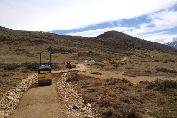 Compacted gravel walking track being formed through open hillside country, with civil contractors completing recreation construction and siteworks. The image highlights walking track construction, park construction, erosion control and ground stabilisation in a remote landscape.