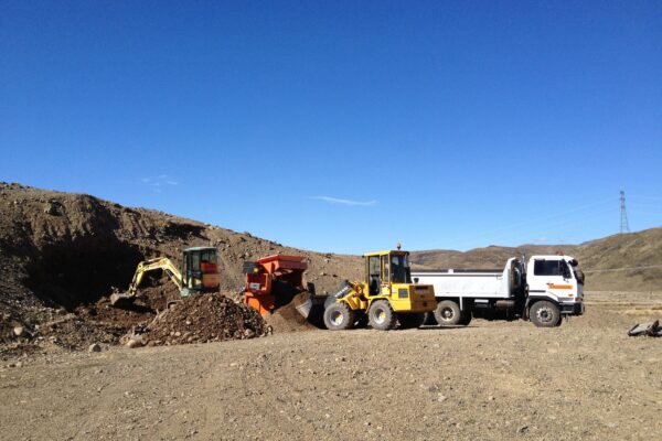 Bulk earthworks and civil construction underway on a rural development site, with excavation machinery, loaders and trucks moving material. This image shows earthworks contractors, site preparation, machinery transport and project management for large scale siteworks.