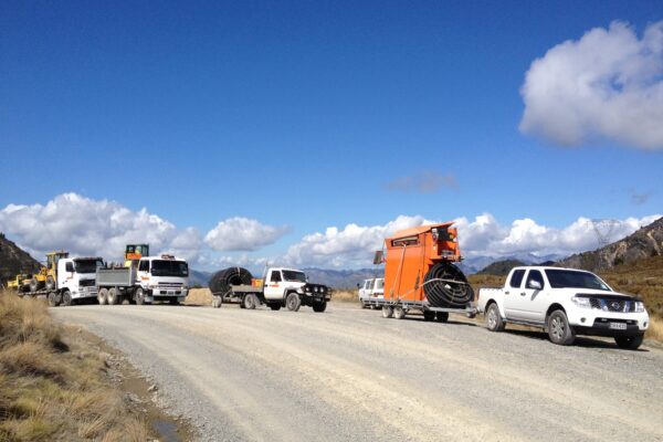 Civil contractors and machinery transport vehicles lined up on a remote gravel road during walking track construction and siteworks. The image shows project management, excavation equipment, earthworks contractors and civil construction support in a rural environment.