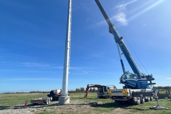Crane lifting equipment to the top of a newly installed pole during power infrastructure and transmission line construction works. This image highlights civil construction, tower installation, overhead infrastructure, machinery transport and siteworks managed by civil contractors in New Zealand.