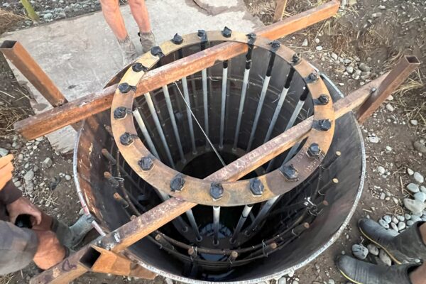 Close-up of a reinforcing cage and circular foundation casing prepared for a pole foundation during civil construction works. The image shows foundation construction, concrete structure preparation, anchoring and piling, bored piles and project management for utility infrastructure.