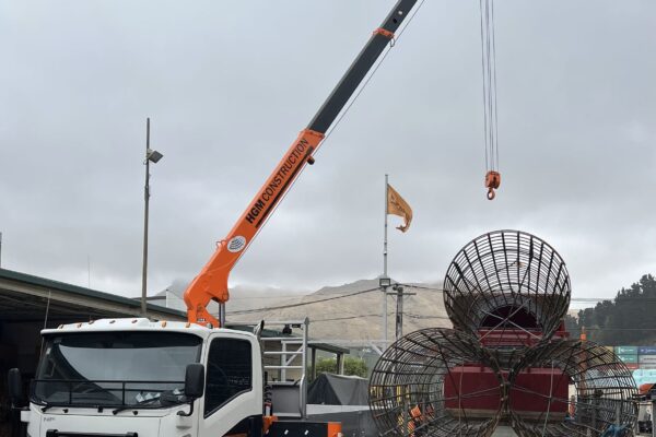 Crane truck lifting a reinforcing cage from a flatbed trailer for foundation construction and concrete structure works. This image shows civil contractors managing machinery transport, sling operations, anchoring and piling, and project management for overhead infrastructure.