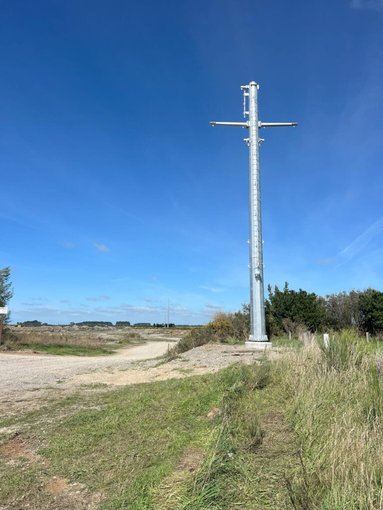 Completed pole installation for power infrastructure and transmission line construction in a rural landscape. The image shows overhead infrastructure, tower installation, civil construction and utility infrastructure delivered by civil contractors.
