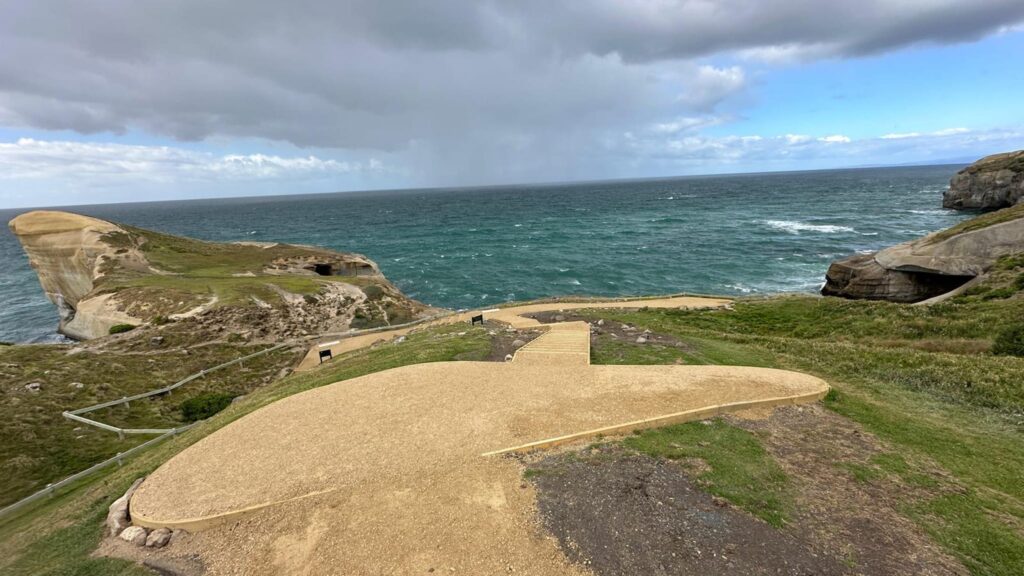 Coastal walking track construction with a finished gravel path and viewing area above the shoreline. The image shows recreation construction, erosion control, siteworks and civil construction designed to improve safe access through a coastal landscape.