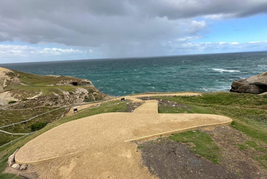 Coastal walking track construction with a finished gravel path and viewing area above the shoreline. The image shows recreation construction, erosion control, siteworks and civil construction designed to improve safe access through a coastal landscape.