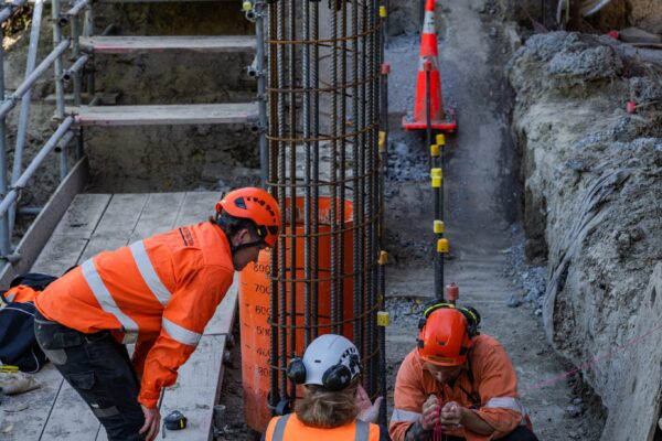Civil construction crew installing steel reinforcement beside excavation works for a retaining walls and concrete structure project. The image shows site contractors completing foundation construction, slope retention and detailed site preparation in a confined area.