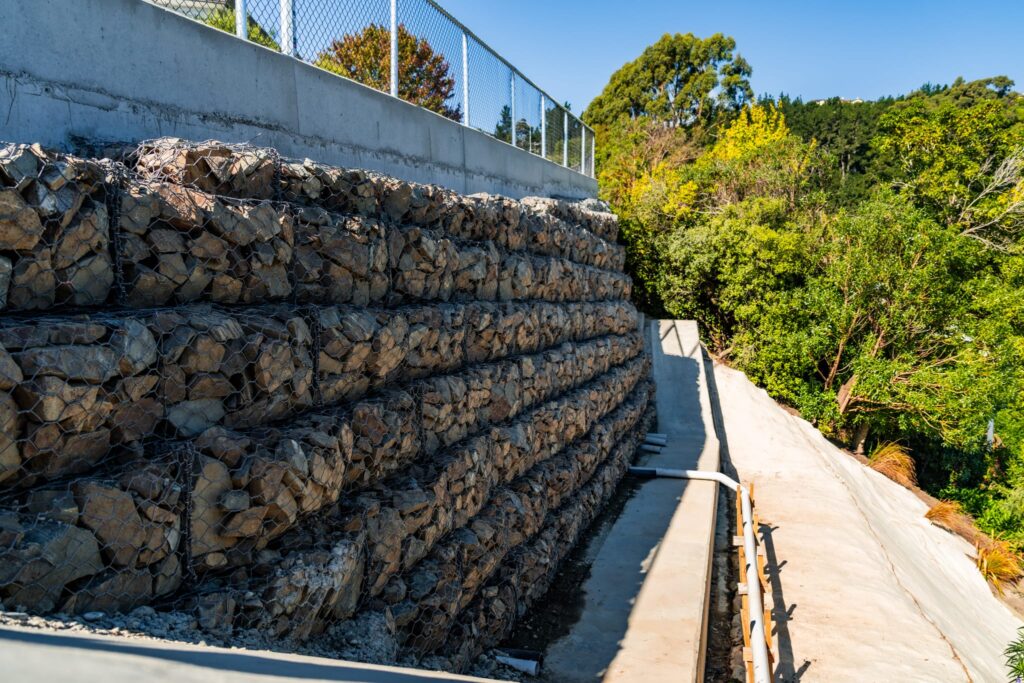 Completed retaining walls with gabion baskets and concrete structure elements supporting a steep accessway. This civil construction project demonstrates slope retention, ground stabilisation and siteworks completed by specialist civil contractors in New Zealand.