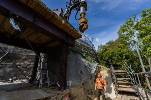 Civil construction workers carrying out excavation and retaining walls work beside a concrete structure on a steep residential site. The project shows specialist site construction, drilling services and slope retention work being completed by experienced civil contractors in New Zealand.
